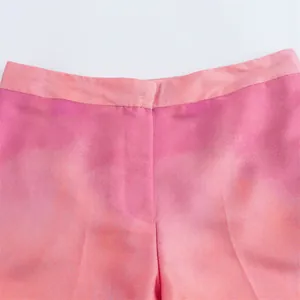 Detail view of pink tie-dye satin trousers showing waistband and fabric texture