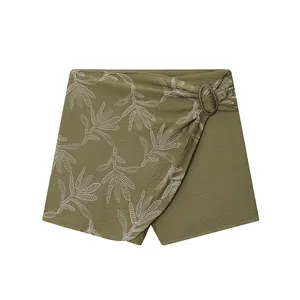 Detailed front view of olive green wrap shorts featuring white botanical leaf embroidery