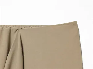 Macro detail view of khaki asymmetric skirt fabric and elasticated waistband stitching