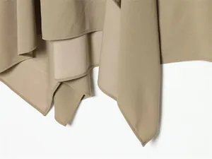 Close-up view of the khaki asymmetrical hemline on a high neck two-piece skirt set