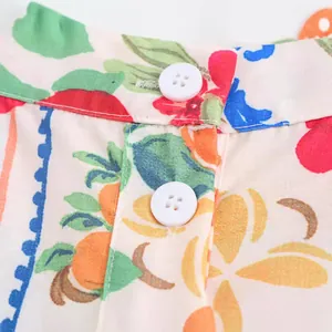 Detailansicht eines Damen-Urlaubssets mit Blumen- und Fruchtdruck sowie weißen Knöpfen.