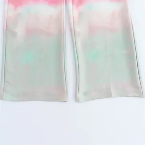 Detail shot of the silky satin fabric and tie-dye print on straight-leg trousers