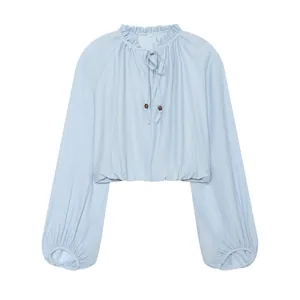 Detailed view of light blue crop top with ruffled collar and wooden bead drawstring