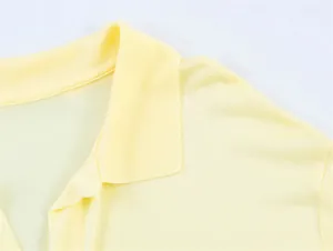 Primo piano del colletto a costine e del tessuto di una polo gialla a maniche lunghe.