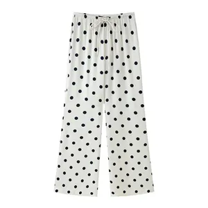 Detailed view of white wide-leg trousers featuring a classic black polka dot pattern