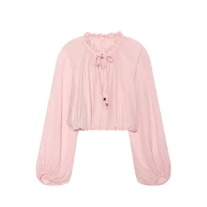 Close-up detail of a pink cropped blouse with ruffled collar and voluminous lantern sleeves