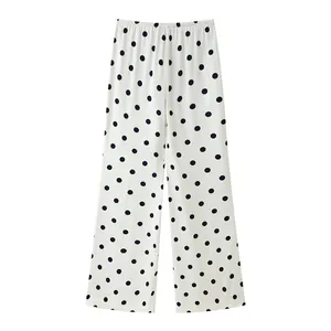 Macro detail view of white wide-leg trousers featuring classic black polka dot pattern