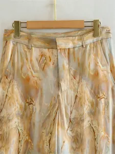 Close-up of tie-dye silk satin pants showing marble print and fabric texture.