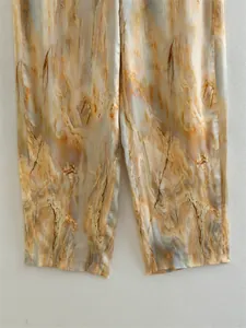 Close-up detail shot of tie-dye marble print satin trousers with smooth texture
