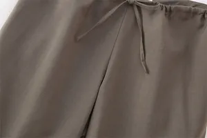 Dettaglio della vita elasticizzata con coulisse di un paio di pantaloni marroni testurizzati.