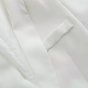 Détail macro d'une poche et d'un revers de blazer blanc montrant le tissu de qualité.