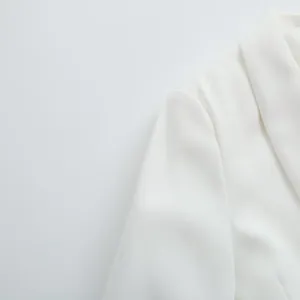 Détail de la manche et du col à revers d'un blazer blanc montrant la texture