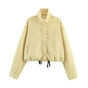 Close-up of yellow jacket with black polka dots featuring high collar and drawstring.