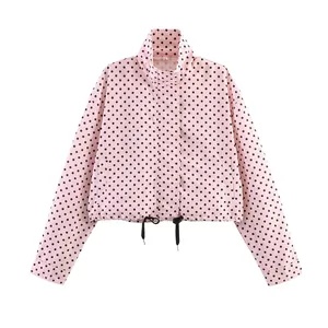 Detailed view of a pink jacket with black polka dots and a drawstring hem