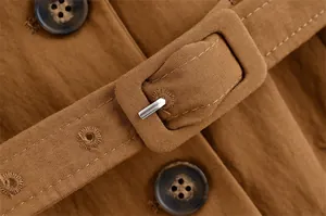 Close-up detail of a brown linen suit jacket belt buckle showing fine textured fabric.