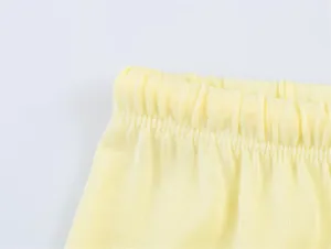 Dettaglio ravvicinato di un pantalone in maglia gialla con vita elastica e trama