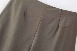 Dettaglio ravvicinato di pantaloni color marrone oliva da donna con pinces e trama del tessuto