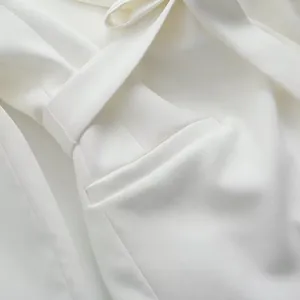 Détail en gros plan d'un blazer blanc tendance montrant la texture de la poche et ceinture