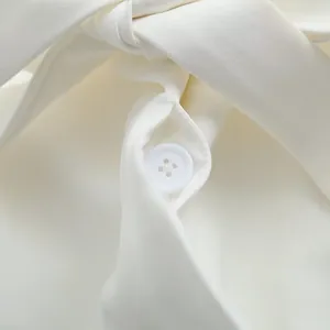 Détail d'un bouton blanc sur un blazer professionnel avec texture de tissu de qualité.