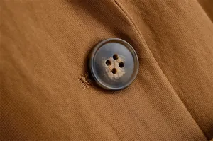 Macro detail shot showing the button and linen fabric texture of a brown blazer jacket