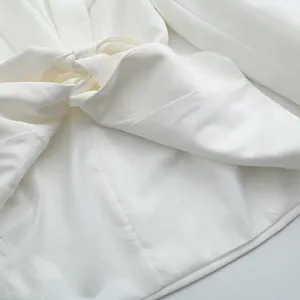 Gros plan détaillé sur un élégant blazer blanc avec un détail de nœud à la taille stylé