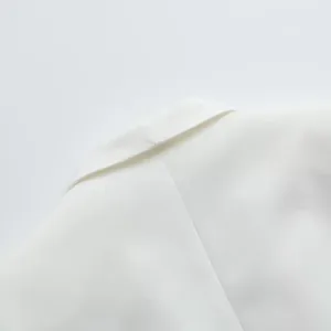 Détail du col d'un blazer blanc montrant la texture du tissu de haute qualité.