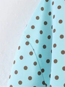 Close-up detail of light blue fabric with brown polka dot pattern and fine stitching detail.