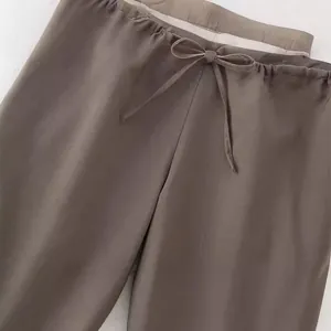 Dettaglio dei pantaloni marroni a vita alta con cordoncino regolabile per l'estate.