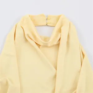Detailed view of yellow cowl neck top featuring elegant double back button closure
