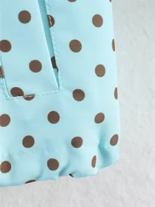 Macro detail of light blue fabric with brown polka dot pattern and fine stitching