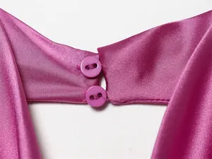 Primer plano de un top halter de satén rosa con un elegante detalle de doble botón trasero