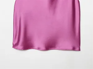 Detalle de cerca del dobladillo finamente cosido de un top de satén de seda color rosa