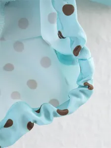 Macro view of light blue fabric with brown polka dots and elasticized edge detail