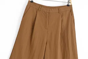 Detailed close-up of brown casual linen mid-rise shorts featuring front pleats and side pockets