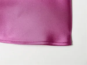 Vista macro que muestra la textura suave y el dobladillo del top halter de satén rosa