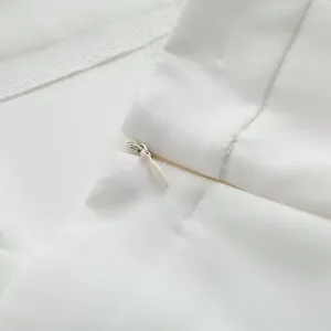 Vue détaillée d'une fermeture éclair invisible blanche sur un pantalon de tailleur large