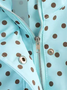 Macro detail showing the silver zipper and metal snap button on blue polka dot jacket