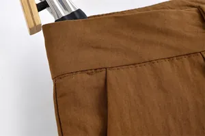 Close-up of brown linen fabric and stitching detail on mid-waist casual shorts.