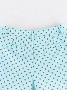 Close-up detail of light blue summer shorts with brown polka dots and back pocket design