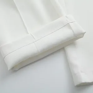 Gros plan sur les coutures et l'ourlet replié d'un pantalon de costume blanc à jambes larges.