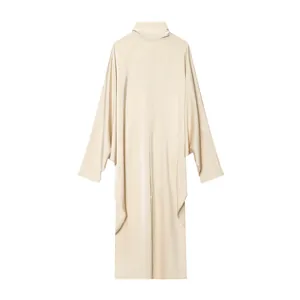 Gros plan sur le tissu drapé fluide et le col montant de cette robe longue crème.