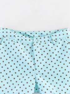 Detail view of light blue shorts with brown polka dots and button closure