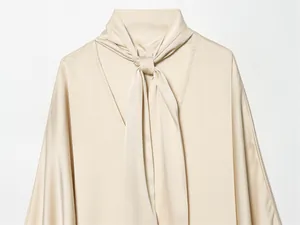 Gros plan d'une robe élégante en satin champagne avec un détail de col à nouer sophistiqué