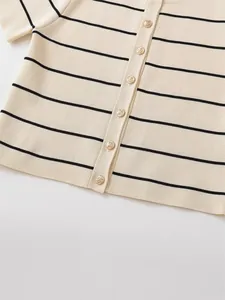 Close-up view of cream striped knit top with decorative gold buttons and fine texture