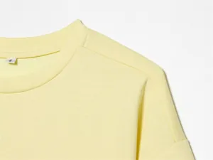 Dettaglio ravvicinato del colletto di una t-shirt giallo chiaro con etichetta taglia S