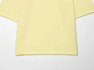 Dettaglio di una maglietta in cotone giallo pallido con elegante spacco laterale