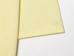 Dettaglio ravvicinato dell'orlo a doppia cucitura di una maglietta in cotone giallo chiaro.