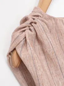 Close-up detail of the twisted shoulder knot on a striped linen-style fabric.