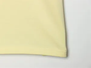 Primo piano dell'orlo a doppia cucitura di una t-shirt in cotone giallo pallido di qualità.