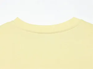 Primo piano del girocollo a costine di una maglietta giallo pallido con cuciture.